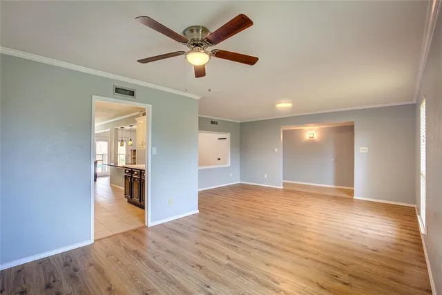 an empty room with wooden floor and a ceiling fan