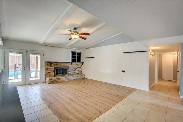 a view of a livingroom with a fireplace a ceiling fan and windows