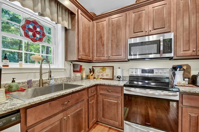 a kitchen with granite countertop a stove a sink and dishwasher wooden cabinets with wooden floor