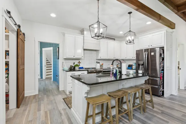 a kitchen with stainless steel appliances granite countertop a sink a stove a refrigerator and island with wooden floor
