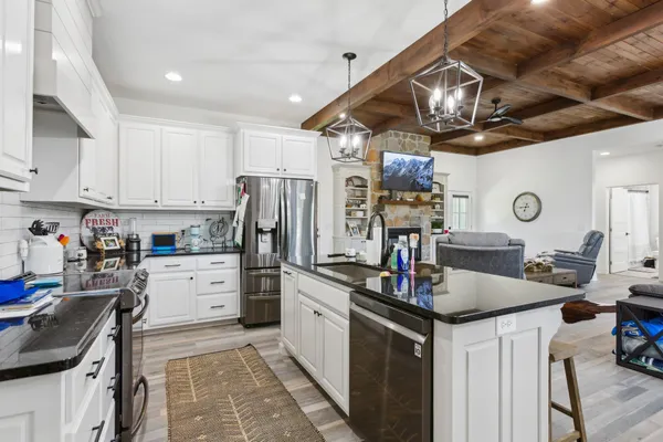 a kitchen with kitchen island granite countertop a sink counter top space appliances and cabinets
