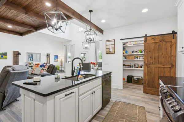 a kitchen with a sink dishwasher a dining table and chairs with wooden floor