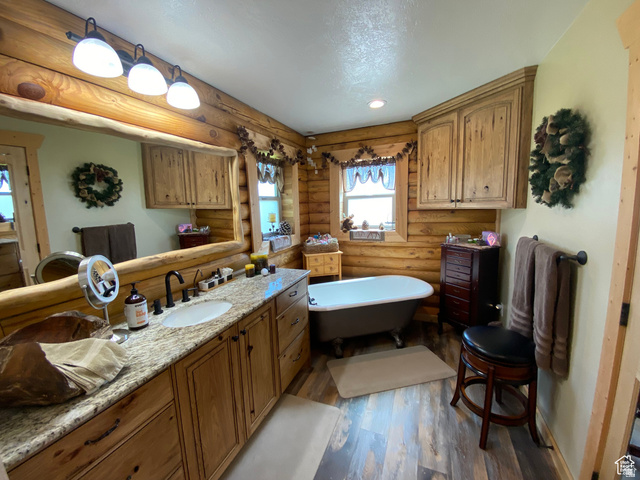 79 Auburn Forest Road Auburn, WY 83111 - Photo 29 of 76 Bathroom featuring log walls, vanity, a freestanding tub, dark wood-style flooring, and recessed lighting