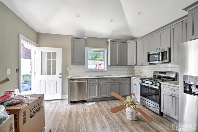 a view of an empty room with wooden floor fireplace and a window
