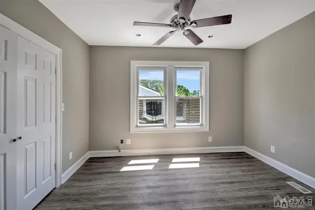 a view of an empty room with window and wooden floor