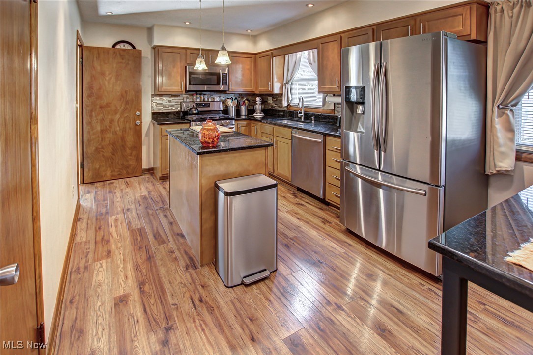 4234 Grafton Road Brunswick, OH 44212 - Photo 2 of 40 Kitchen featuring a kitchen island, decorative backsplash, stainless steel appliances, pendant lighting, and light wood-type flooring