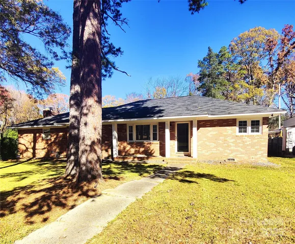 a front view of a house with a yard outdoor seating and covered with trees