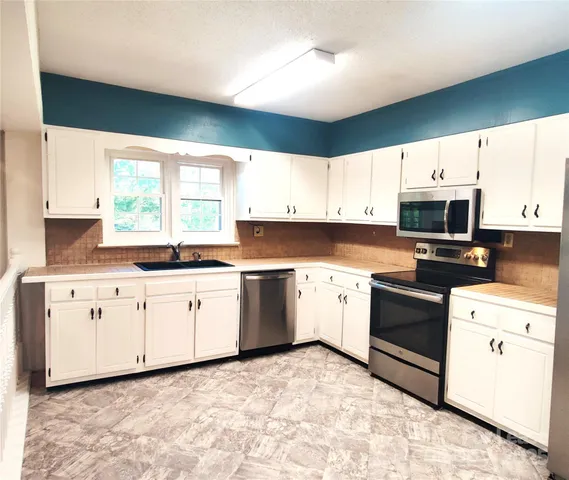 a kitchen with granite countertop white cabinets white stainless steel appliances with a sink and dishwasher