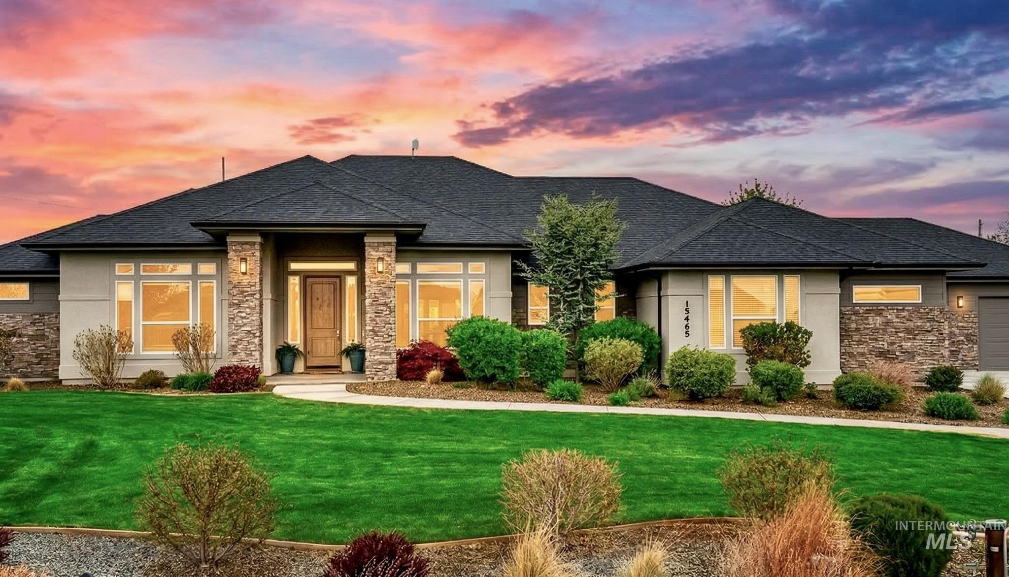Prairie-style house with stone siding, a front lawn, stucco siding, and a shingled roof