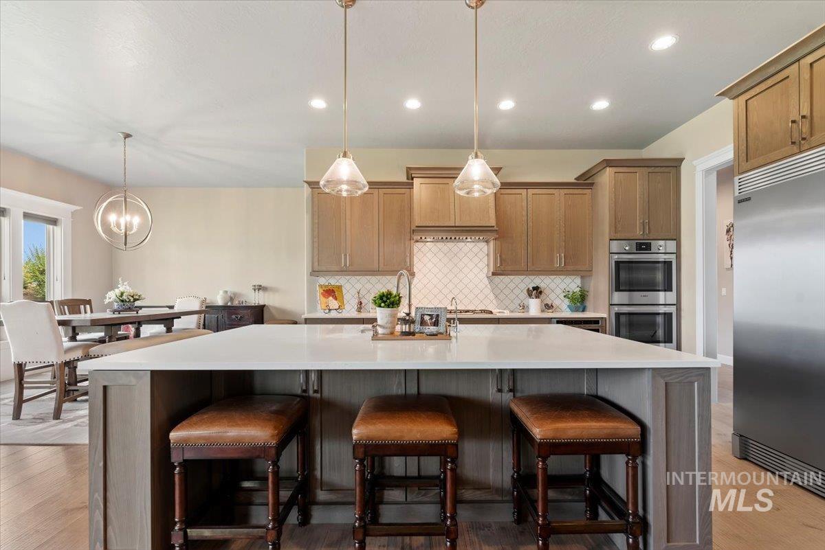 15465 Syrah Court Caldwell, ID 83607 - Photo 11 of 50 Kitchen featuring appliances with stainless steel finishes, backsplash, a spacious island, light countertops, and a chandelier