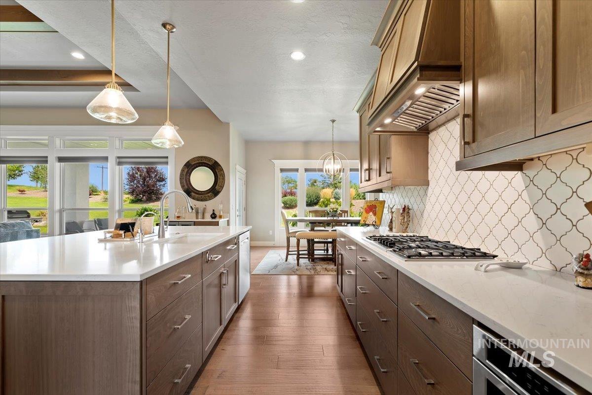 15465 Syrah Court Caldwell, ID 83607 - Photo 12 of 50 Kitchen featuring light countertops, decorative backsplash, dark wood finished floors, custom exhaust hood, and recessed lighting