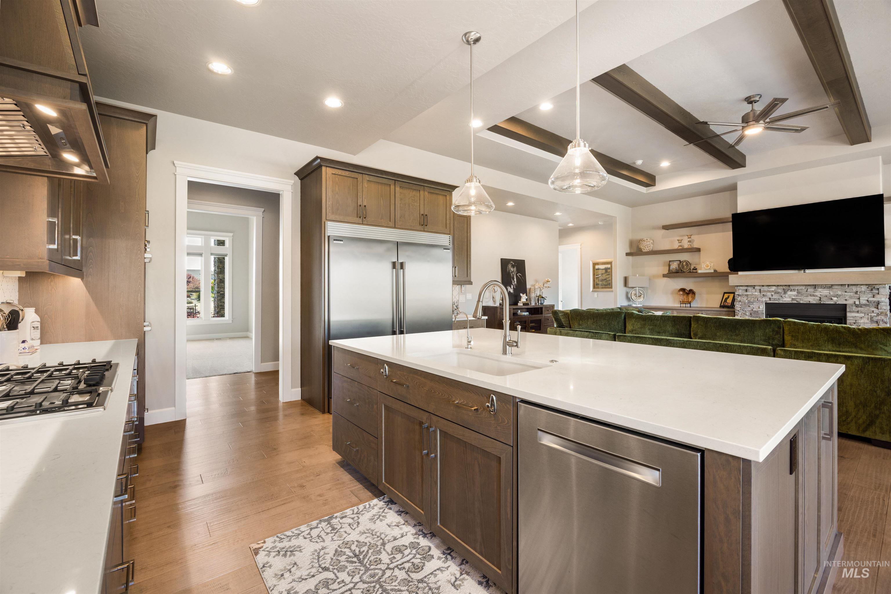 15465 Syrah Court Caldwell, ID 83607 - Photo 44 of 45 Kitchen with open floor plan, stainless steel appliances, a kitchen island with sink, pendant lighting, and a stone fireplace