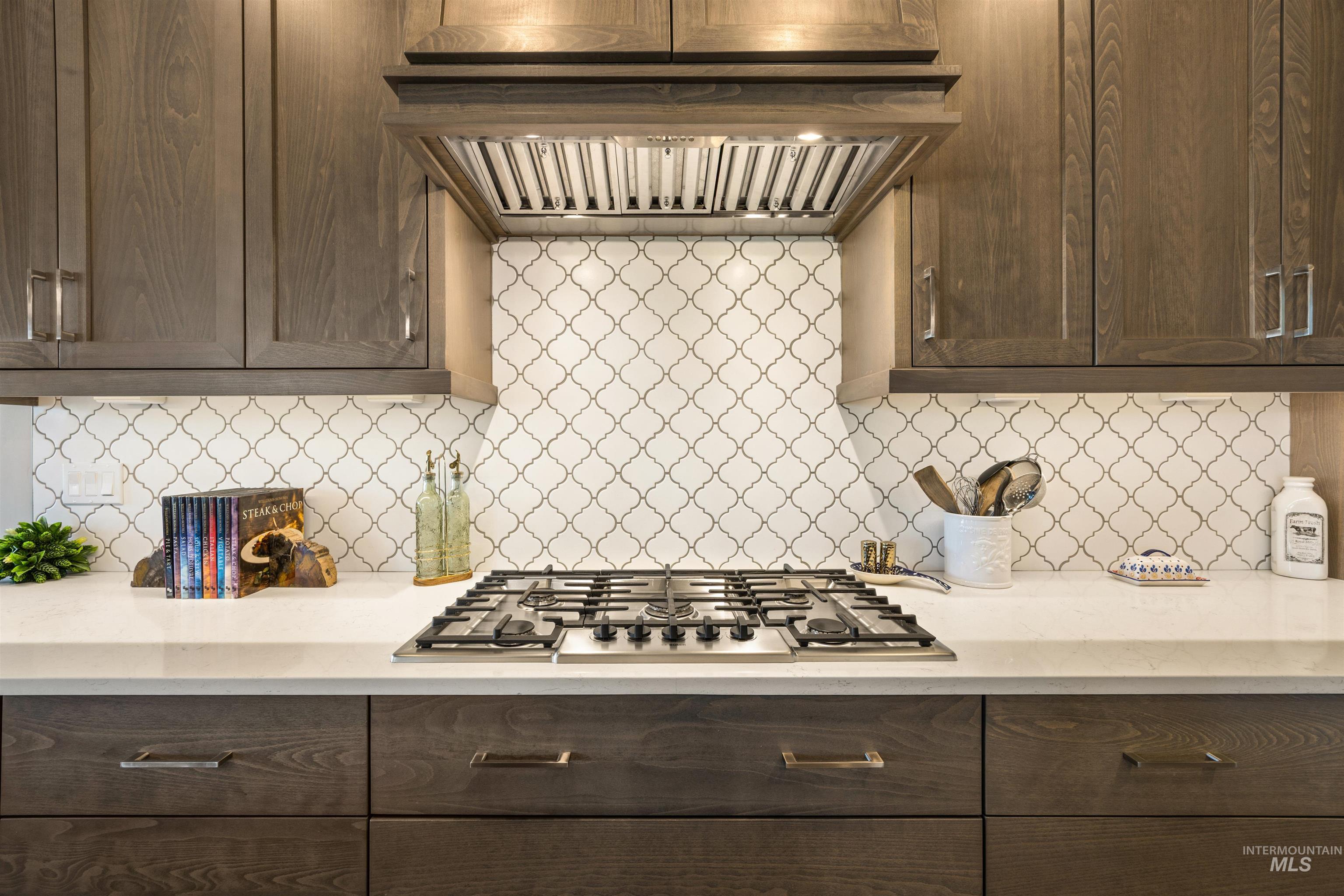 15465 Syrah Court Caldwell, ID 83607 - Photo 15 of 45 Kitchen with extractor fan, light stone countertops, dark wood finish cabinets, stainless steel gas stovetop, and backsplash