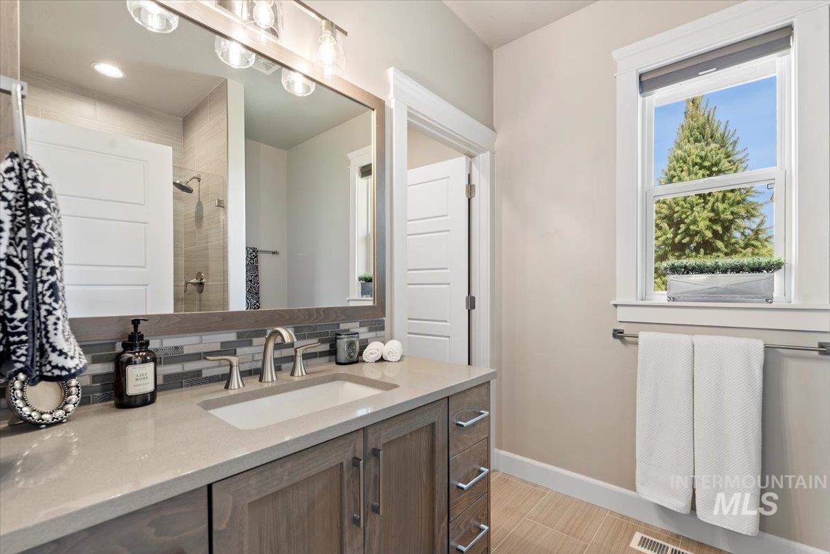 15465 Syrah Court Caldwell, ID 83607 - Photo 24 of 50 Full bathroom featuring vanity, a tile shower, and decorative backsplash