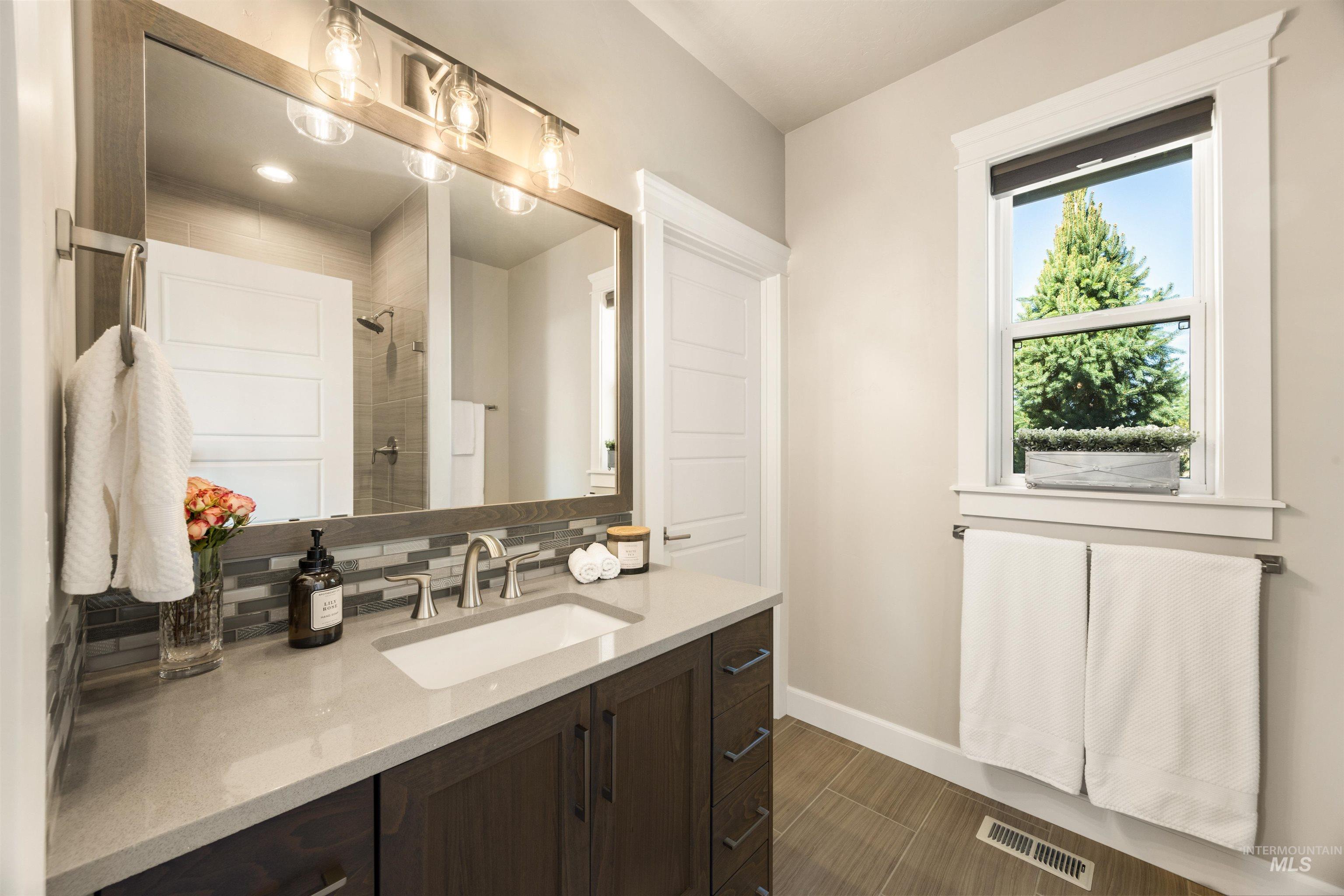 15465 Syrah Court Caldwell, ID 83607 - Photo 28 of 45 Bathroom featuring decorative backsplash, vanity, a tile shower, and wood tiled floors