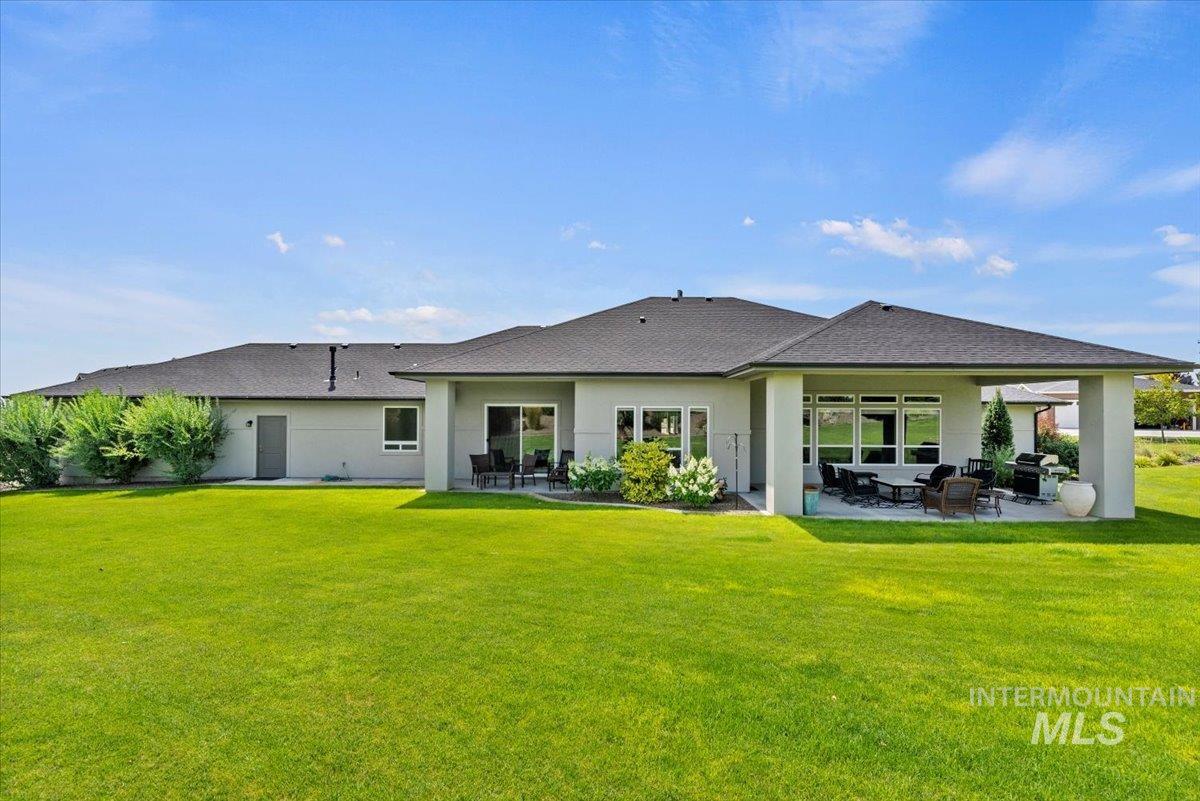 15465 Syrah Court Caldwell, ID 83607 - Photo 33 of 50 Back of property featuring a patio area, a yard, roof with shingles, and stucco siding