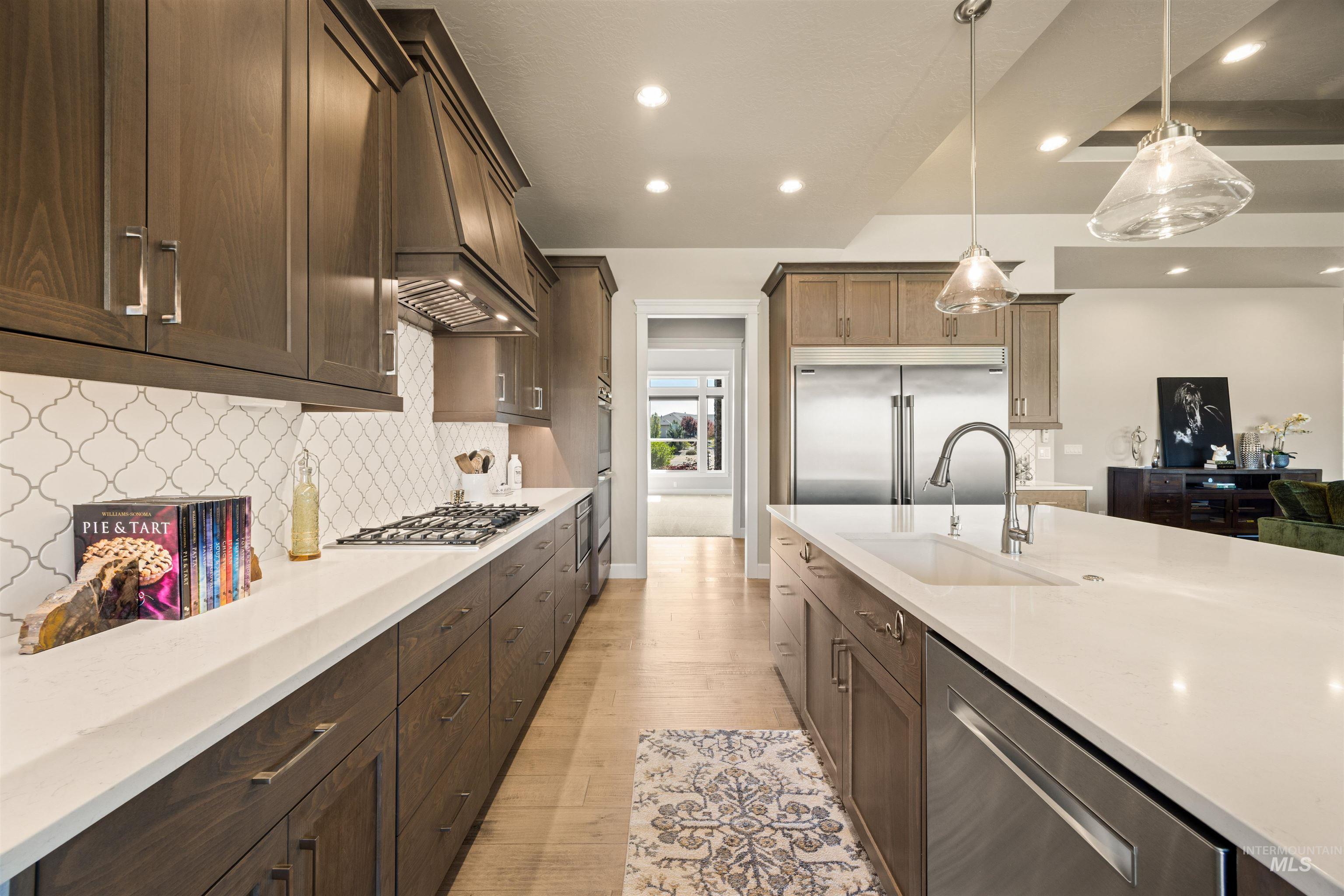 15465 Syrah Court Caldwell, ID 83607 - Photo 4 of 45 Kitchen with stainless steel appliances, light stone counters, decorative light fixtures, light wood-style flooring, and dark wood finish cabinetry