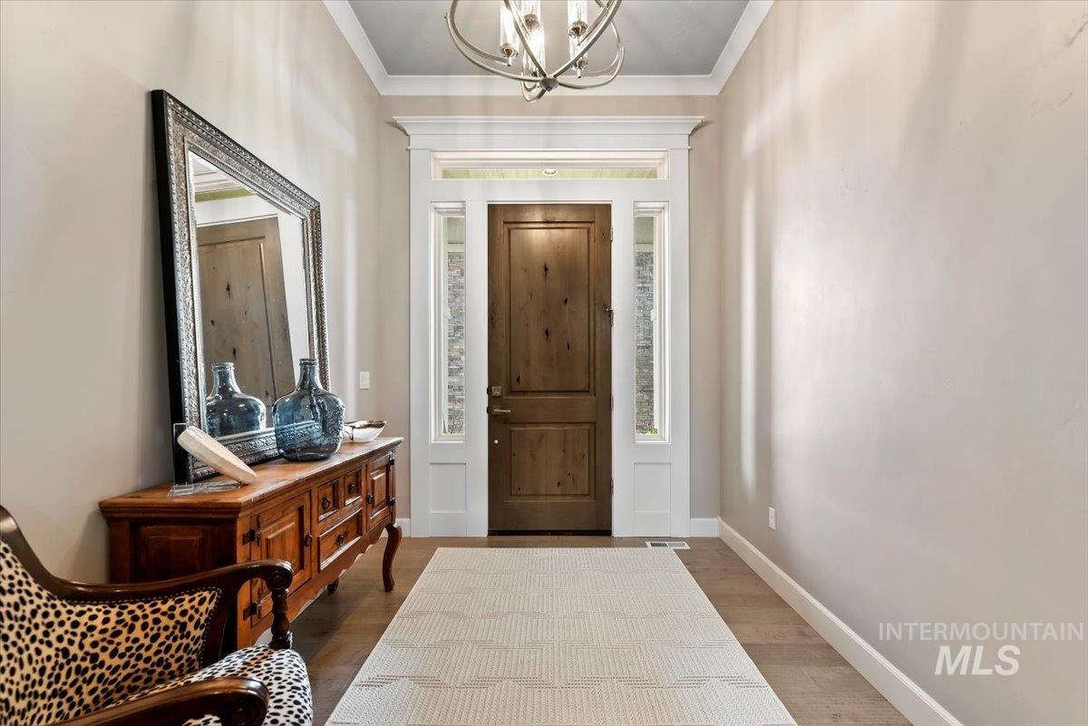15465 Syrah Court Caldwell, ID 83607 - Photo 6 of 50 Foyer entrance with ornamental molding, a chandelier, and wood finished floors