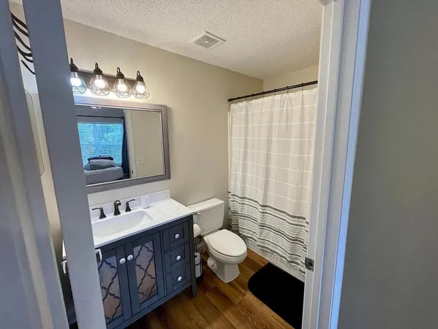 a bathroom with a sink a toilet a mirror and shower