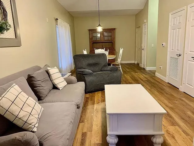 a living room with furniture a window and wooden floor