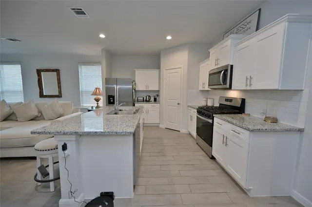 a large kitchen with stainless steel appliances kitchen island granite countertop a sink and cabinets