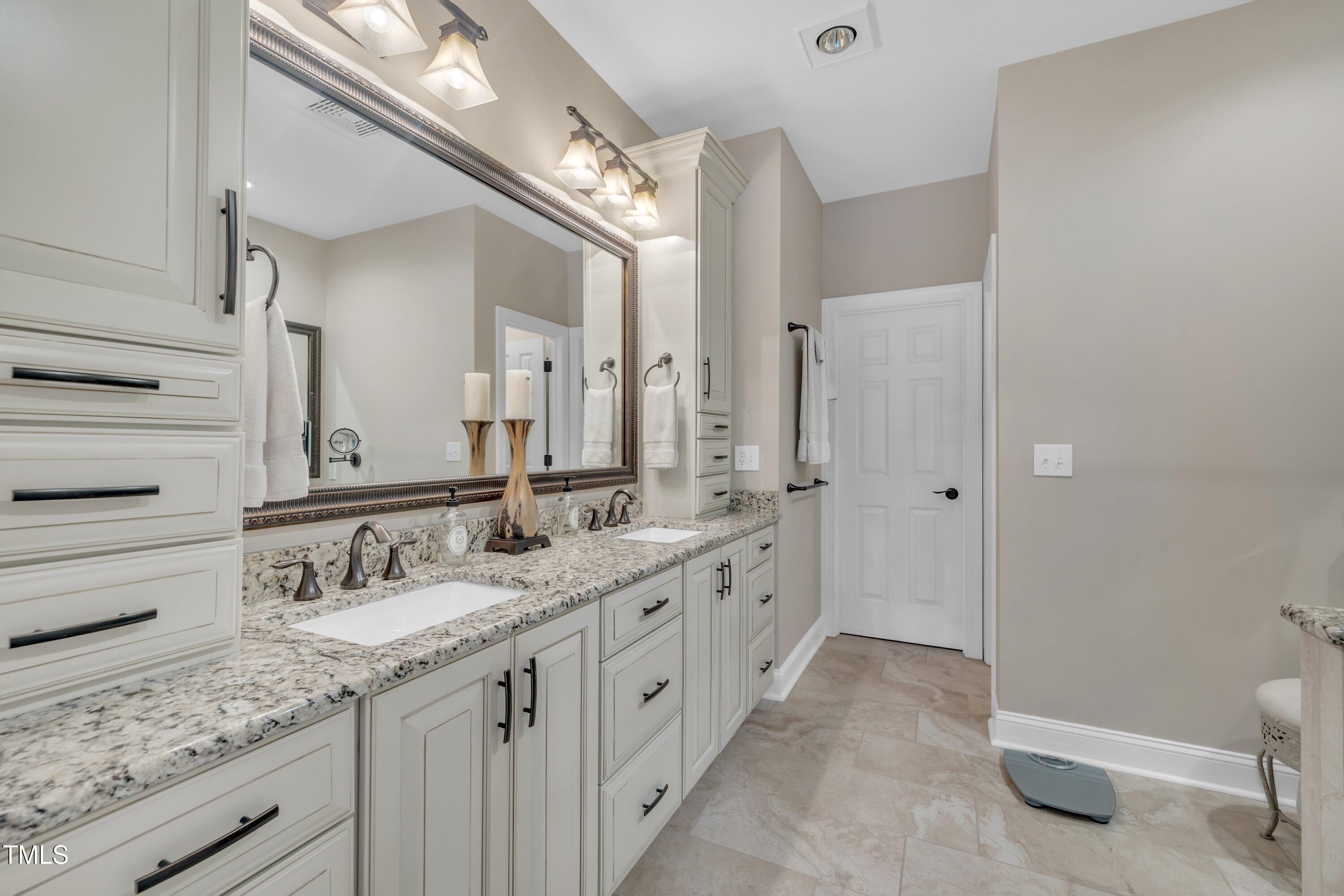 4802 Glenmist Court Raleigh, NC 27612 - Photo 23 of 52 a spacious bathroom with a granite countertop sink and a mirror