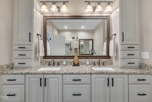 a bathroom with a granite countertop double vanity sink and a mirror