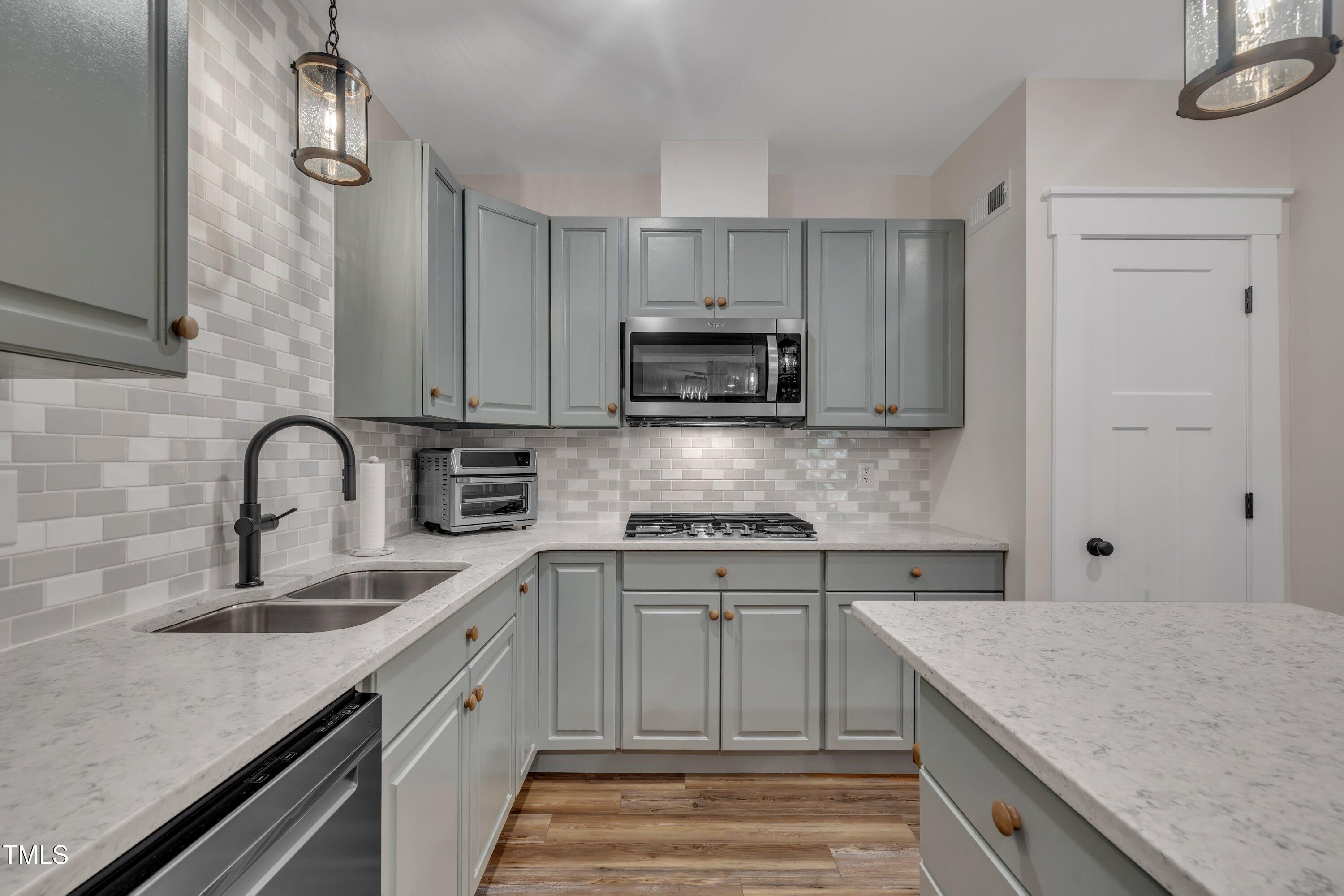 4802 Glenmist Court Raleigh, NC 27612 - Photo 43 of 52 a kitchen with stainless steel appliances granite countertop a sink dishwasher a stove and a refrigerator with wooden cabinets
