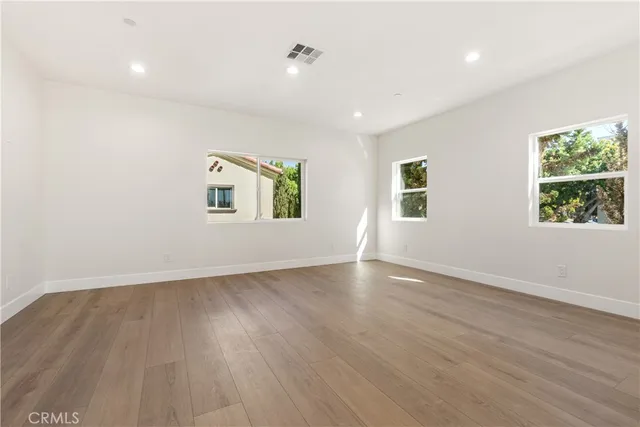 an empty room with wooden floor and windows
