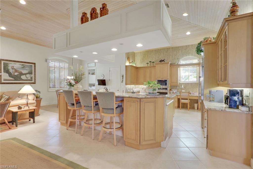 435 Terracina Way Naples, FL 34119 - Photo 11 of 50 Kitchen with light brown cabinets, a breakfast bar, light stone countertops, a large island with sink, and wooden ceiling