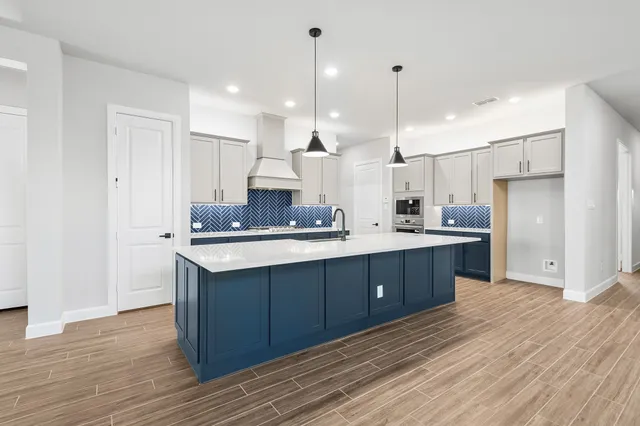 a large kitchen with stainless steel appliances kitchen island granite countertop a sink refrigerator and cabinets