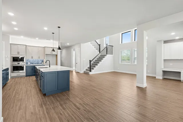 a large living room with stainless steel appliances kitchen view and wooden floor