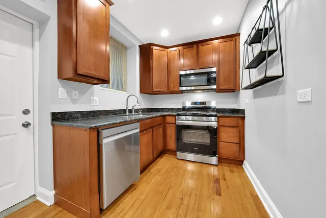 a kitchen with stainless steel appliances granite countertop wooden cabinets a stove top oven a sink and dishwasher