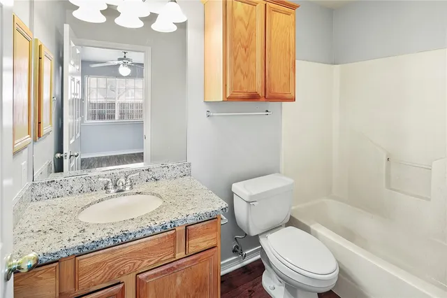 a bathroom with a granite countertop toilet a sink and a mirror