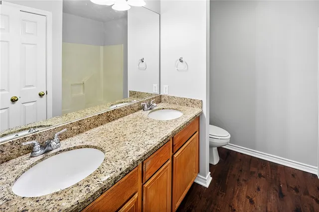 a bathroom with a granite countertop double vanity sink and mirror