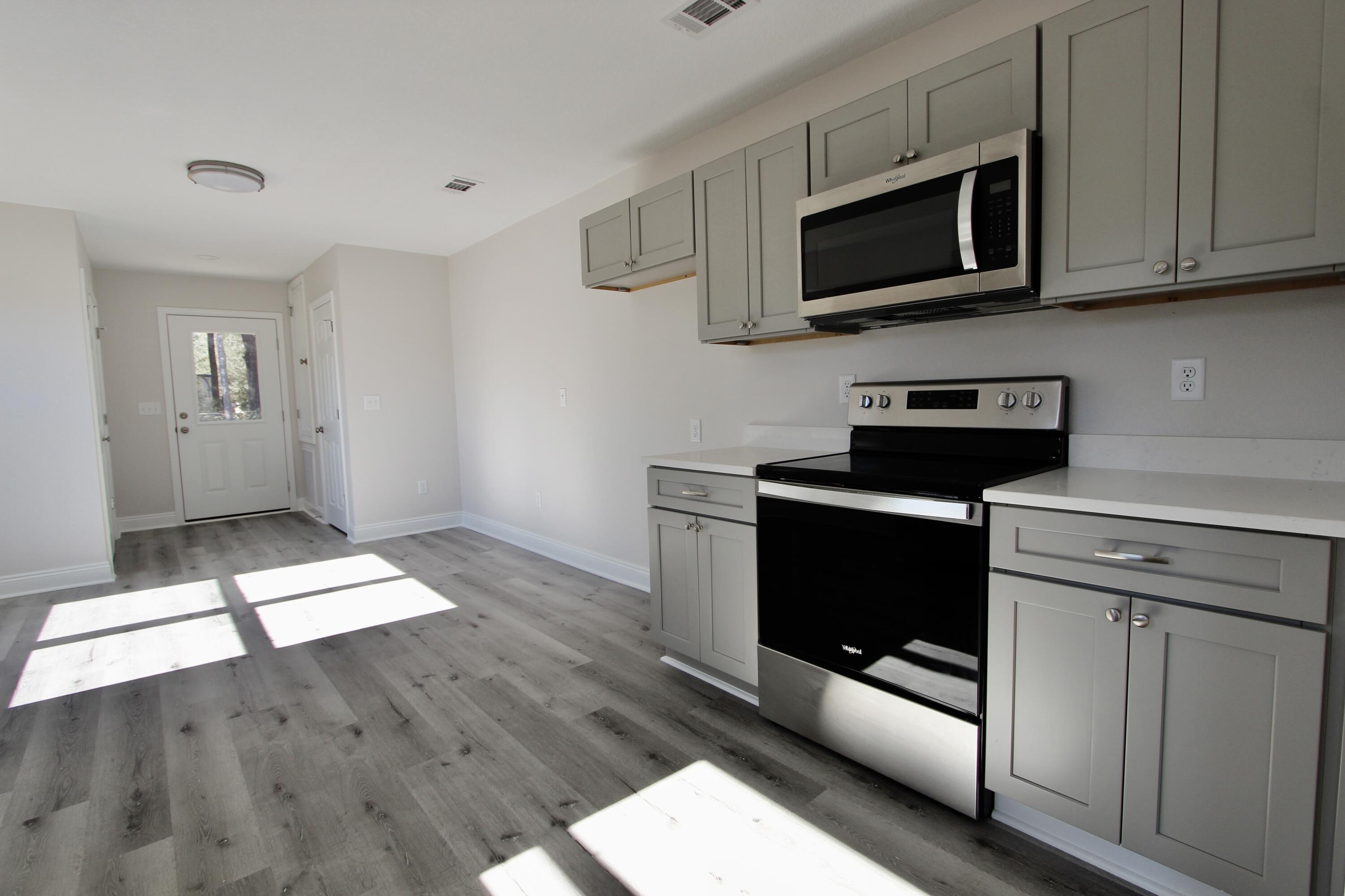 4662 Falcon Way Crestview, FL 32539 - Photo 9 of 20 a kitchen with stainless steel appliances kitchen island granite countertop a stove a microwave and a sink
