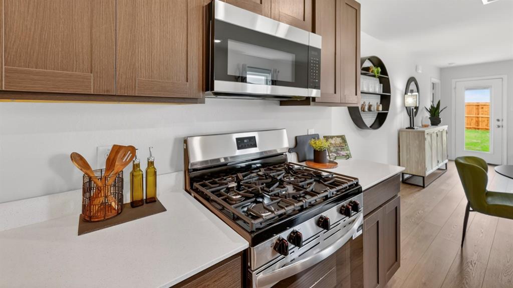 3514 Spring Time Street Terrell, TX 75126 - Photo 4 of 26 Modern kitchen featuring wood-finish cabinetry, stainless steel appliances, white countertops, and wood-finish flooring