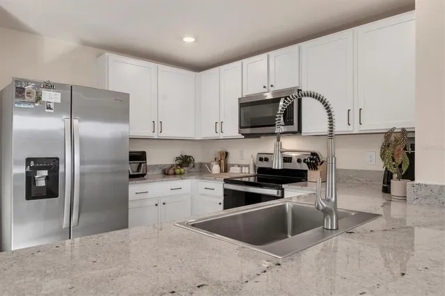 a kitchen with stainless steel appliances granite countertop a refrigerator a stove and a sink