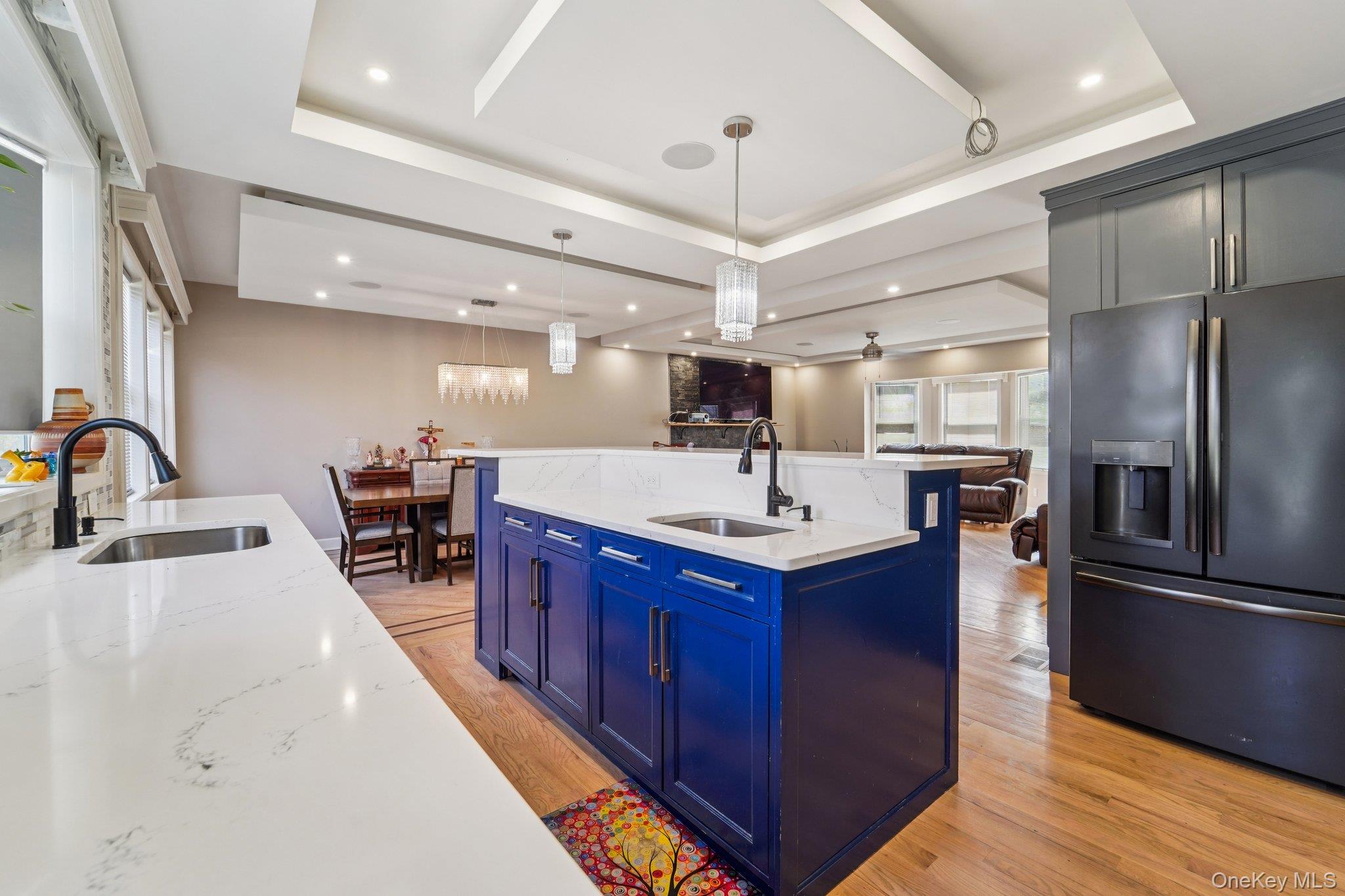 109 Bennett Road Newburgh, NY 12550 - Photo 13 of 41 The open-concept kitchen features a blue island with seating, grey and blue cabinetry, and light countertops, complemented by a tiled backsplash.