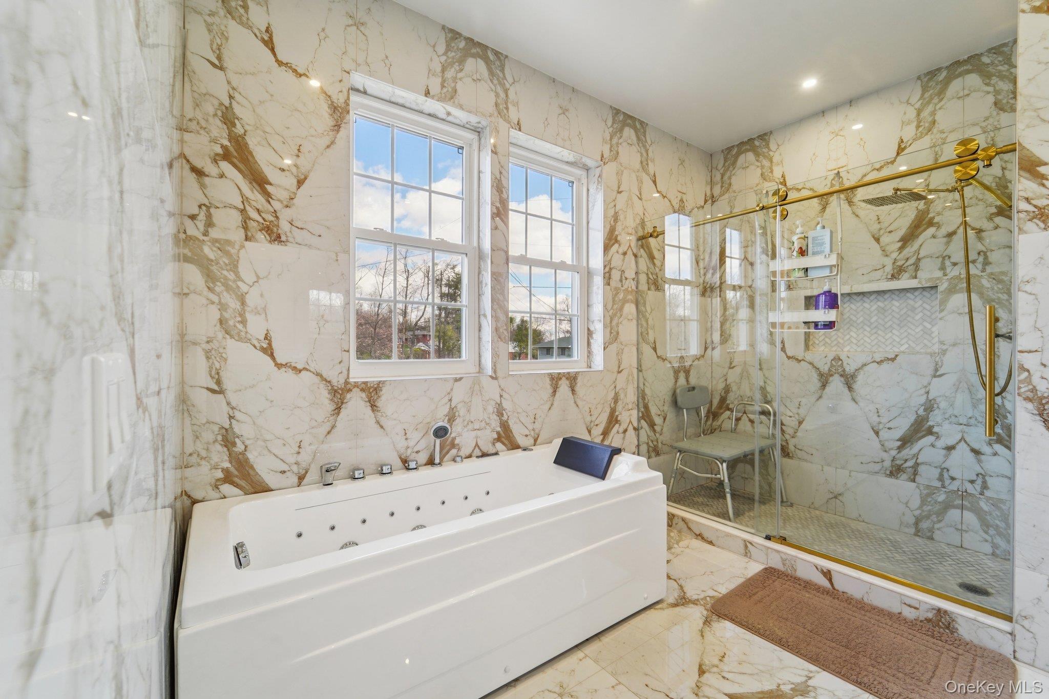 109 Bennett Road Newburgh, NY 12550 - Photo 27 of 41 This luxurious bathroom features a spacious soaking tub with a shower head, and a separate glass-enclosed shower with gold-toned fixtures.