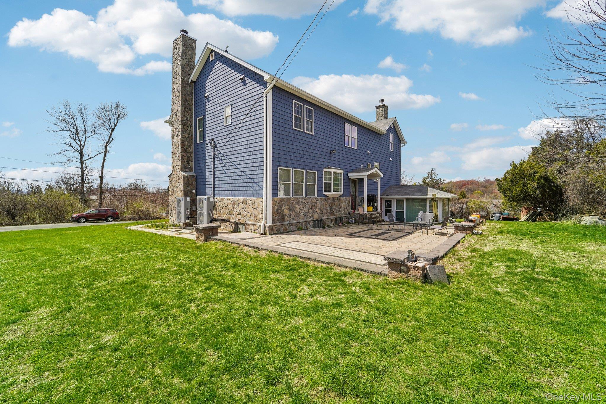 109 Bennett Road Newburgh, NY 12550 - Photo 4 of 41 The property features blue siding, a stone foundation, and a stone paver patio with decorative darker stone accents.