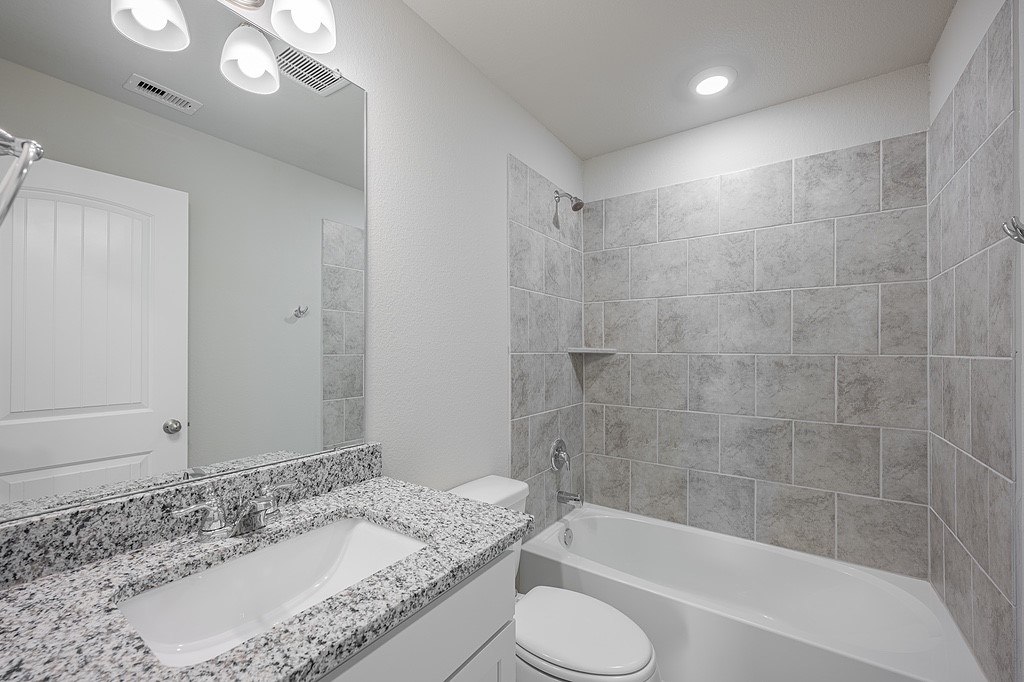 602 Davy Street Brenham, TX 77833 - Photo 12 of 16 a bathroom with a granite countertop sink a toilet and bathtub