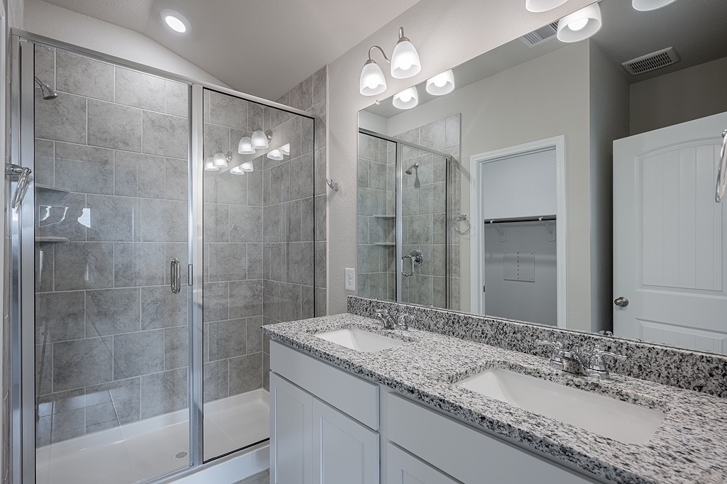 602 Davy Street Brenham, TX 77833 - Photo 10 of 16 a bathroom with a granite countertop sink a large mirror and a shower