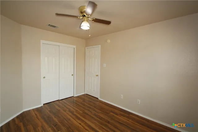 an empty room with wooden floor a ceiling fan and closet