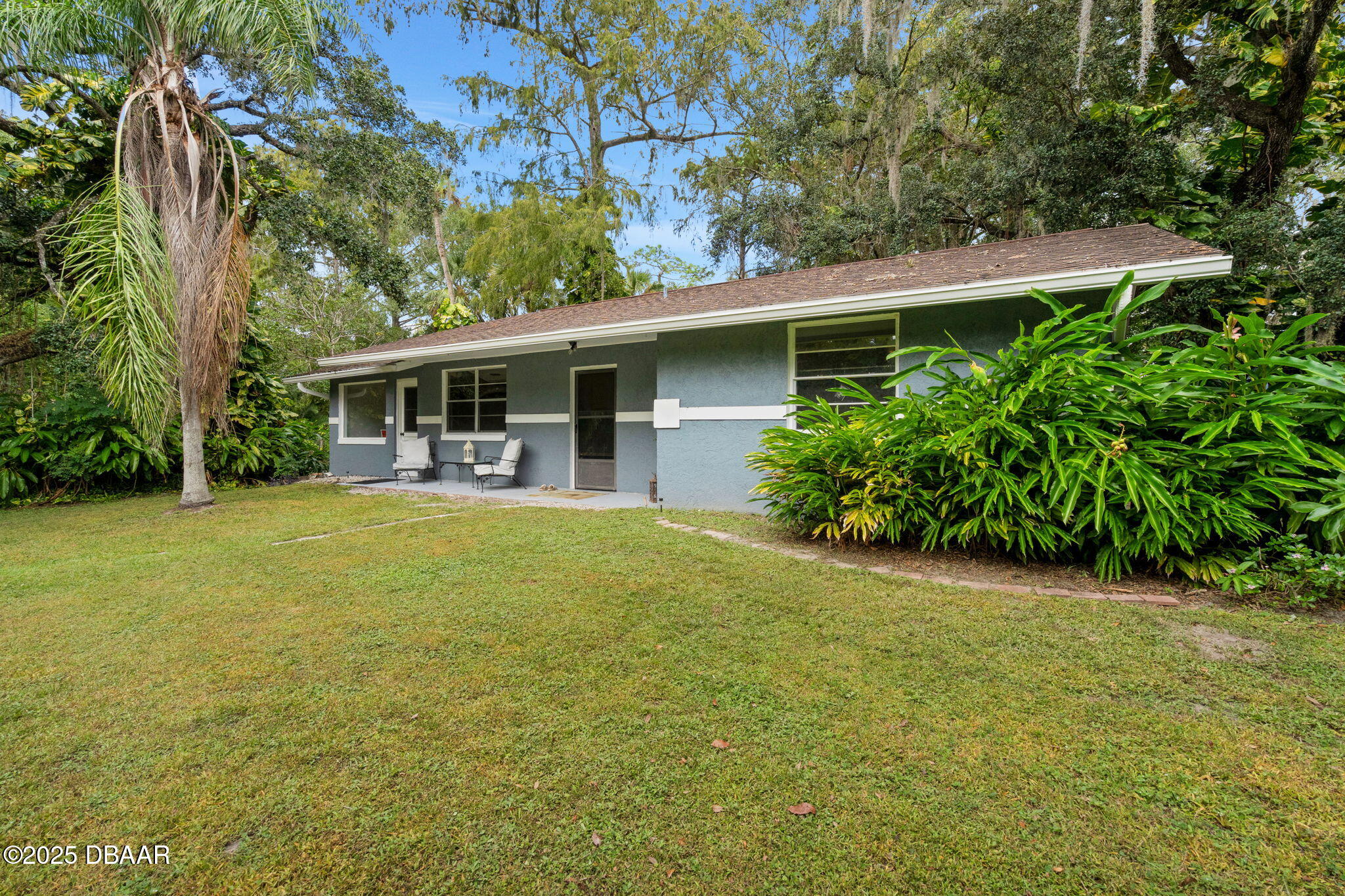 a view of a patio with table and chairs potted plants and large tree