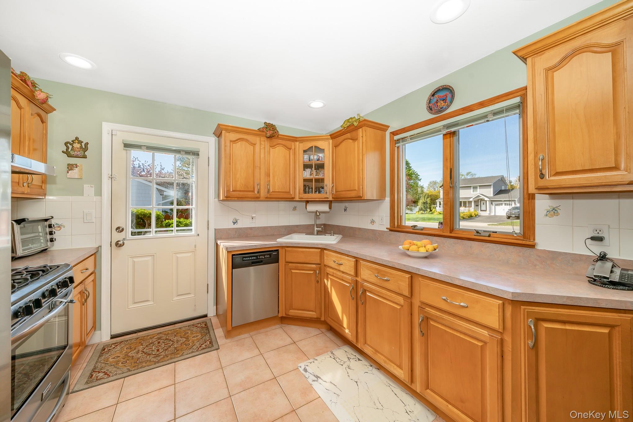 18 Byron Road Commack, NY 11725 - Photo 15 of 32 Kitchen featuring wood cabinetry, stainless steel dishwasher, tile flooring, and a large window