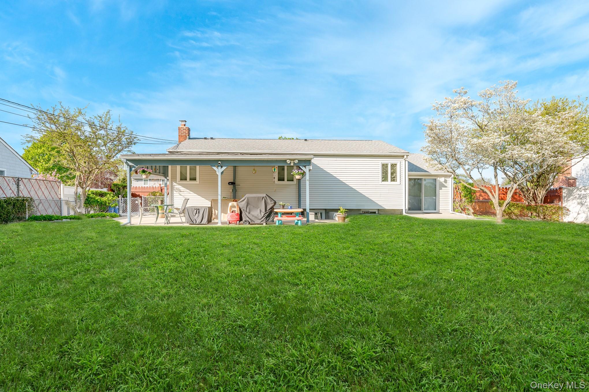 18 Byron Road Commack, NY 11725 - Photo 6 of 32 Expansive green lawn with a covered patio, brick chimney, and mature trees
