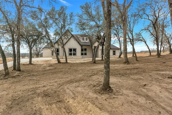 a front view of a house with a yard and large tree