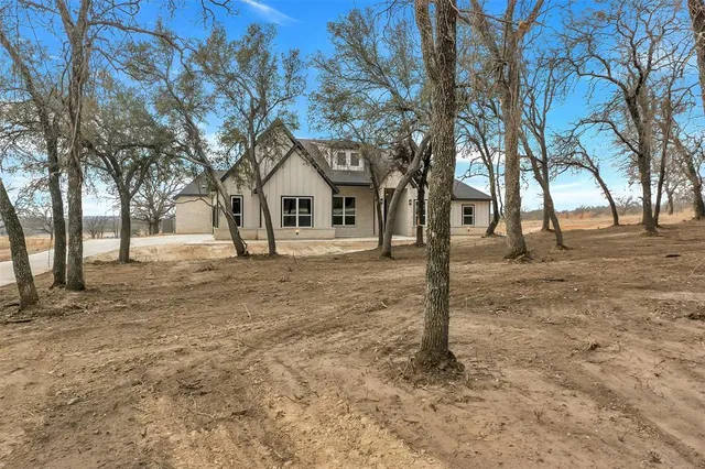 a front view of a house with a yard and large tree