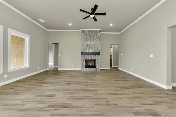 a view of a livingroom with a fireplace a ceiling fan and wooden floor